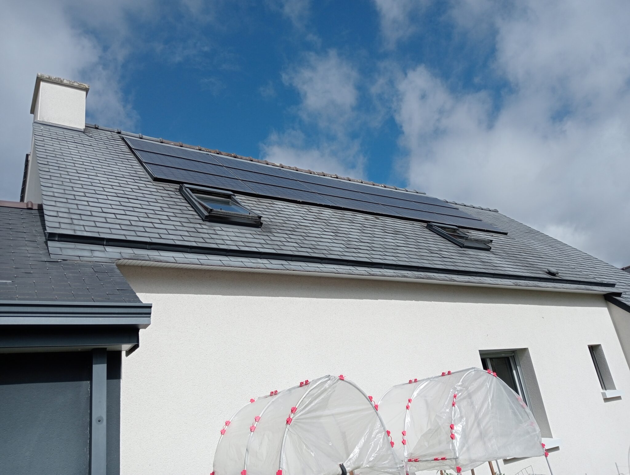 Toit en ardoise avec panneaux solaires et lucarnes.