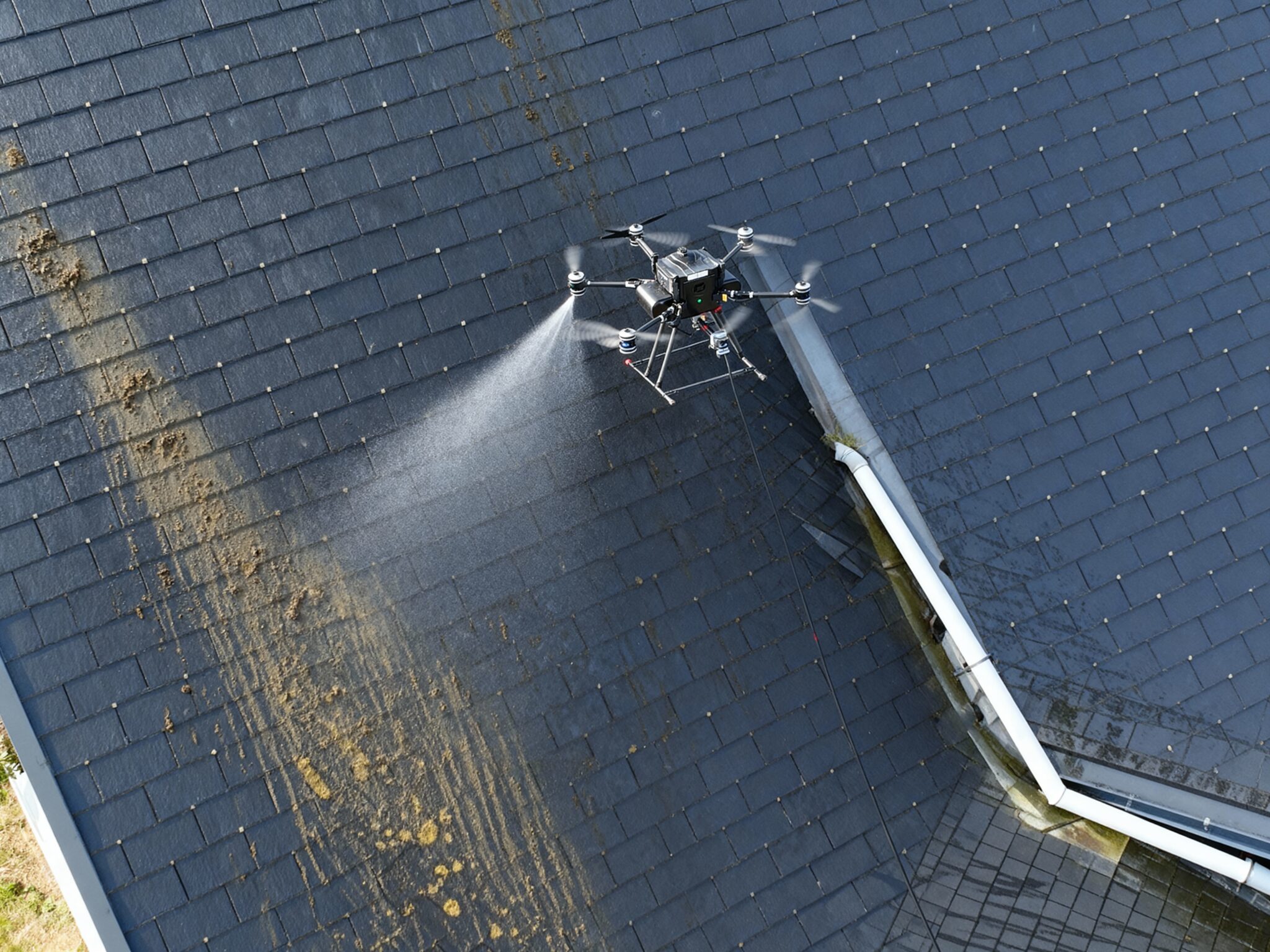 Drone nettoyant un toit en ardoise.